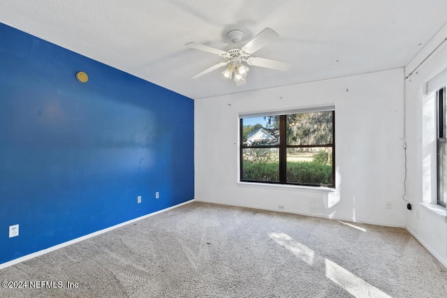 carpeted spare room featuring ceiling fan