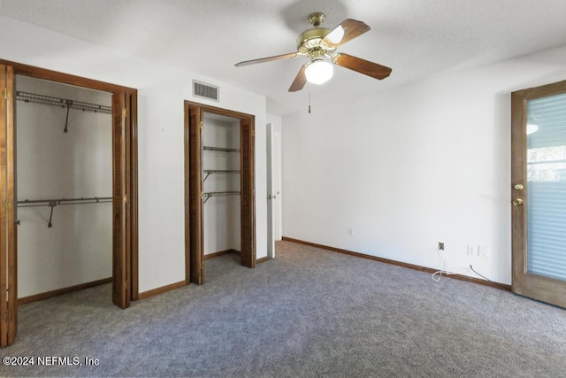 unfurnished bedroom with carpet flooring, ceiling fan, and multiple closets