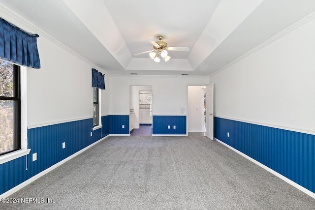 spare room with a tray ceiling, ceiling fan, carpet, and ornamental molding