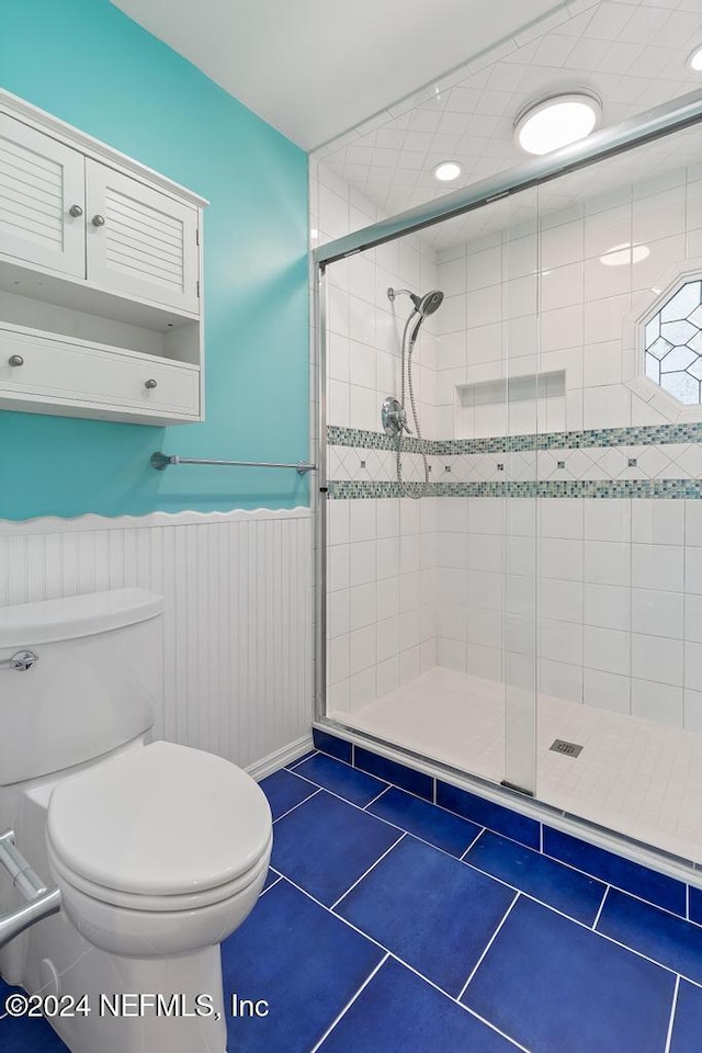 bathroom featuring tile patterned flooring, toilet, and a shower with door