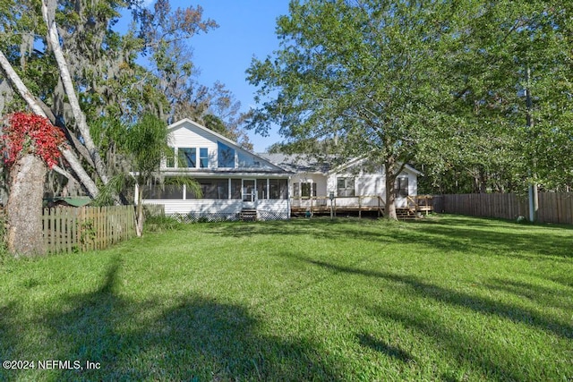 back of property featuring a sunroom, a wooden deck, and a lawn