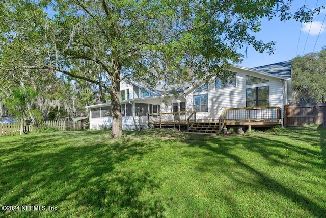 rear view of house with a yard, a wooden deck, and a sunroom