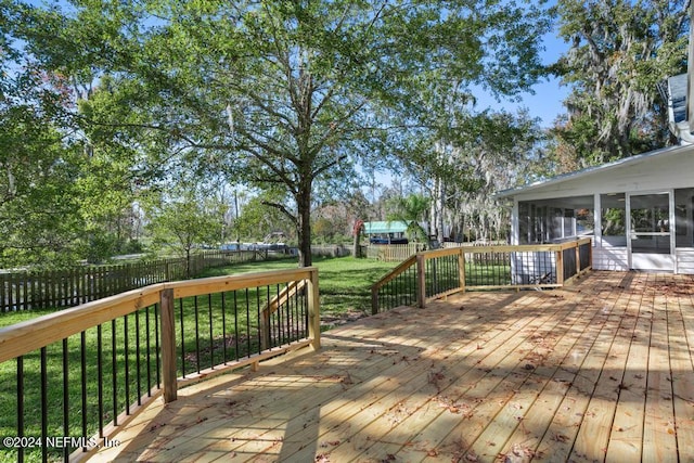 wooden terrace featuring a lawn and a sunroom