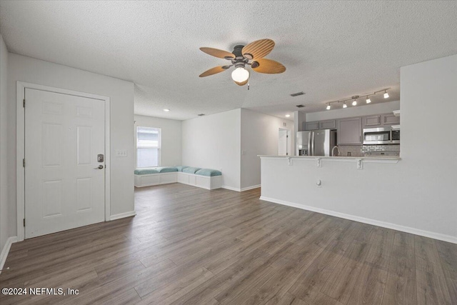 unfurnished living room featuring ceiling fan, dark hardwood / wood-style flooring, and a textured ceiling