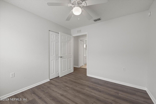 unfurnished bedroom with ceiling fan, dark hardwood / wood-style flooring, and a textured ceiling