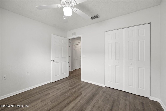 unfurnished bedroom with ceiling fan, a closet, dark wood-type flooring, and a textured ceiling