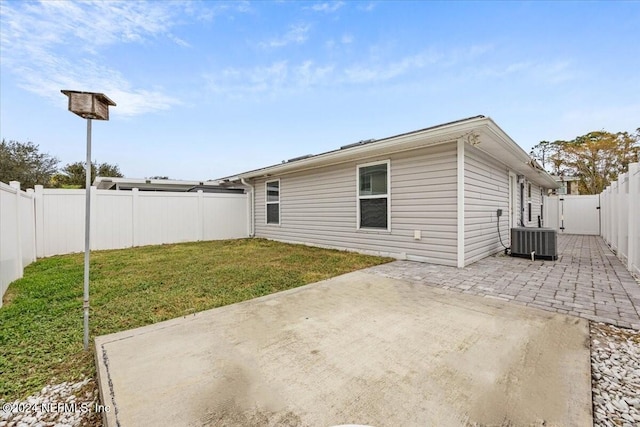 rear view of house featuring a yard, central AC, and a patio area