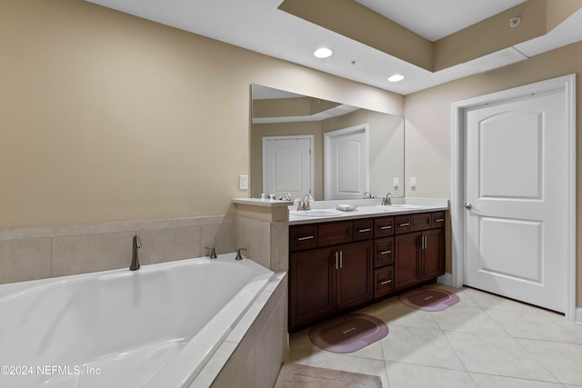 bathroom with tiled bath, tile patterned flooring, and vanity