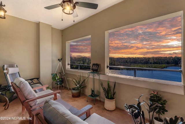 patio terrace at dusk with ceiling fan, a balcony, and a water view