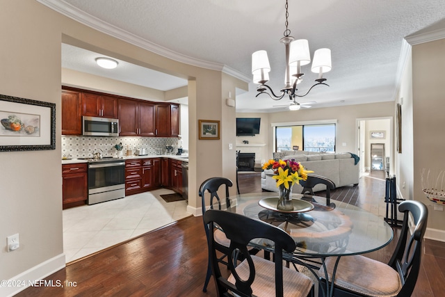 dining space with a textured ceiling, light hardwood / wood-style flooring, a notable chandelier, and crown molding