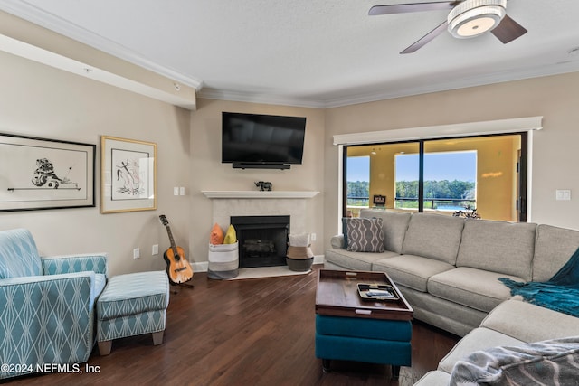 living room with a tiled fireplace, ceiling fan, dark wood-type flooring, and ornamental molding