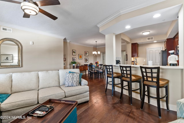 living room with ceiling fan with notable chandelier, dark hardwood / wood-style flooring, ornamental molding, and a textured ceiling