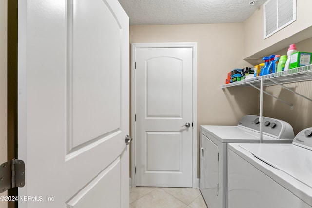 laundry room with light tile patterned floors, a textured ceiling, and independent washer and dryer