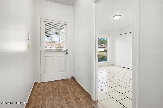 doorway to outside featuring a textured ceiling and light hardwood / wood-style flooring