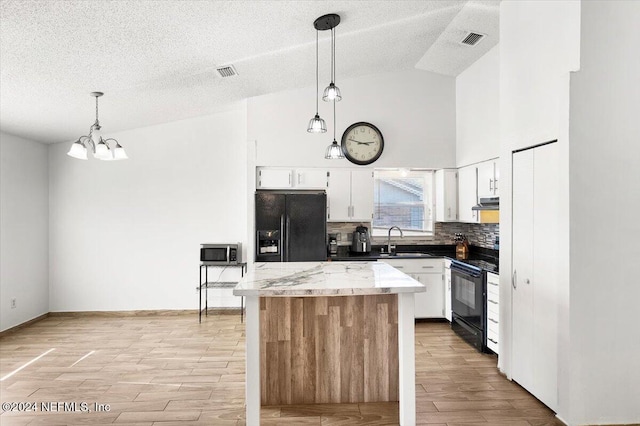 kitchen featuring black appliances, pendant lighting, white cabinetry, and vaulted ceiling