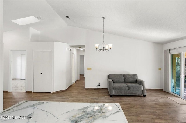 interior space with wood-type flooring, a textured ceiling, a skylight, and a notable chandelier