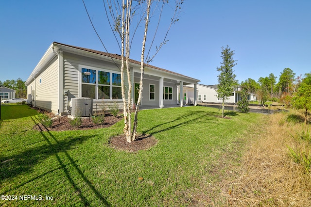 back of property with central AC unit and a lawn