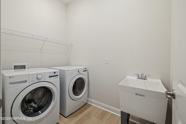 laundry area featuring washing machine and dryer, light hardwood / wood-style flooring, and sink