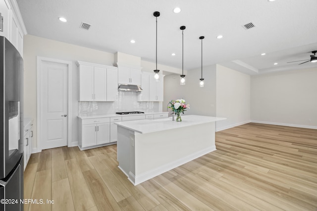 kitchen with white cabinetry, black gas cooktop, light hardwood / wood-style flooring, pendant lighting, and a kitchen island with sink