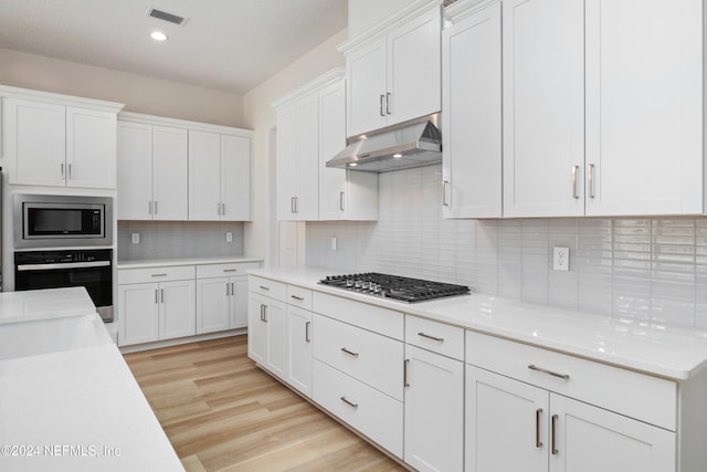 kitchen featuring tasteful backsplash, white cabinetry, stainless steel appliances, and light wood-type flooring