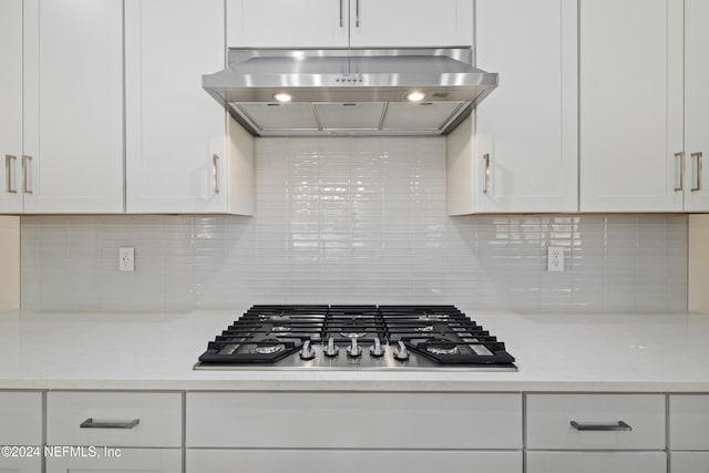 kitchen with light stone countertops, tasteful backsplash, ventilation hood, stainless steel gas cooktop, and white cabinets