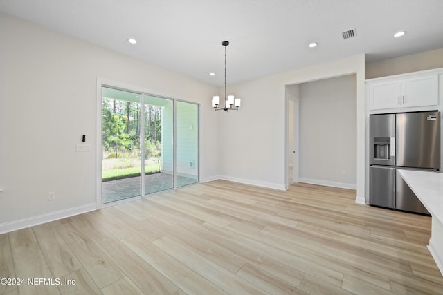 unfurnished dining area with light hardwood / wood-style floors and a notable chandelier