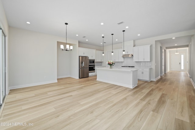 kitchen featuring white cabinets, decorative light fixtures, stainless steel appliances, and an island with sink