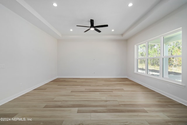 unfurnished room featuring ceiling fan, a raised ceiling, and light hardwood / wood-style flooring