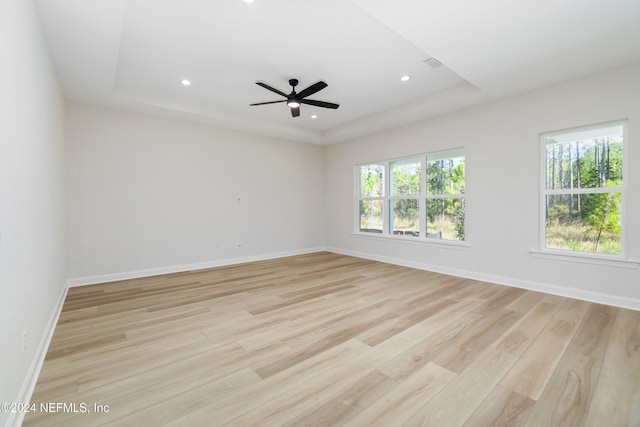 unfurnished room featuring light wood-type flooring, a raised ceiling, and ceiling fan