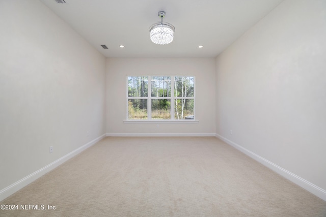 empty room with light carpet and an inviting chandelier