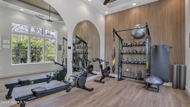 workout room featuring ceiling fan, wood-type flooring, and a high ceiling