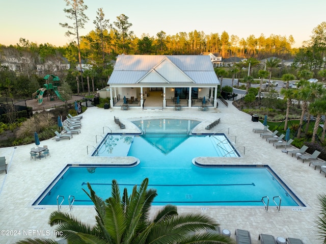 pool at dusk featuring a patio area