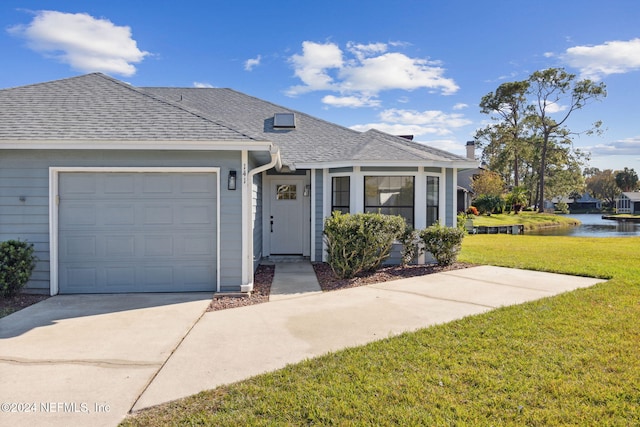 view of front of home with a water view, a garage, and a front lawn