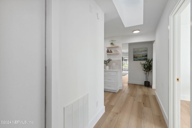 hallway featuring light wood-type flooring and a skylight