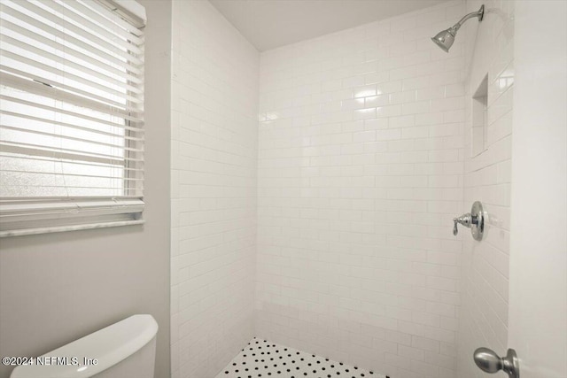 bathroom with a tile shower and toilet