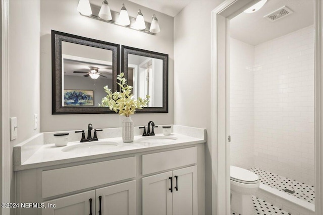 bathroom featuring vanity, tile patterned flooring, ceiling fan, toilet, and a tile shower