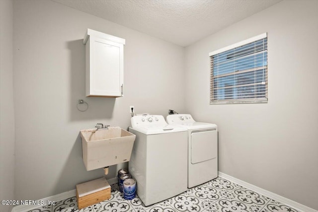 laundry area featuring sink, washer and dryer, cabinets, and a textured ceiling