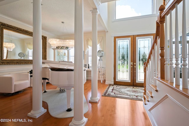 entrance foyer featuring french doors, a high ceiling, a notable chandelier, hardwood / wood-style floors, and a textured ceiling