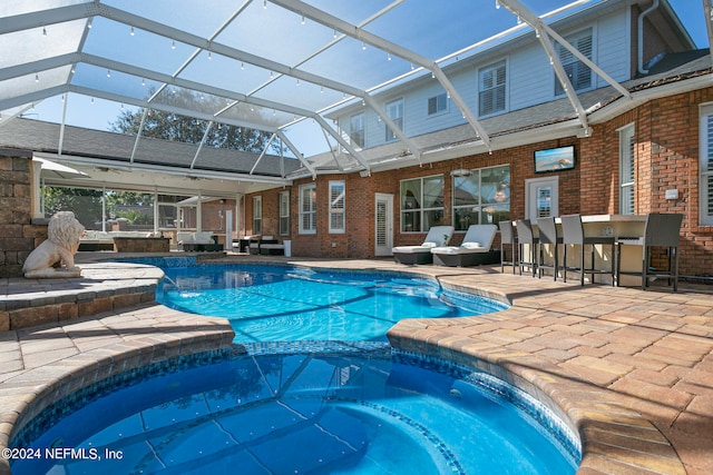 view of pool featuring exterior bar, an in ground hot tub, a lanai, and a patio area