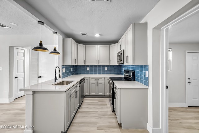 kitchen with pendant lighting, gray cabinetry, sink, light hardwood / wood-style floors, and stainless steel appliances