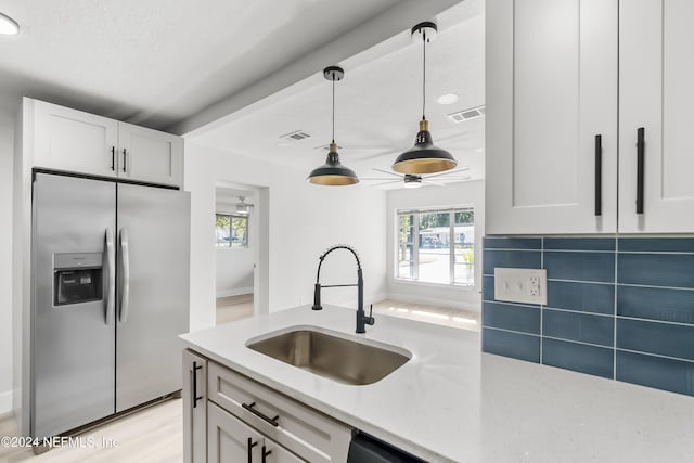 kitchen featuring stainless steel fridge, tasteful backsplash, sink, decorative light fixtures, and white cabinets