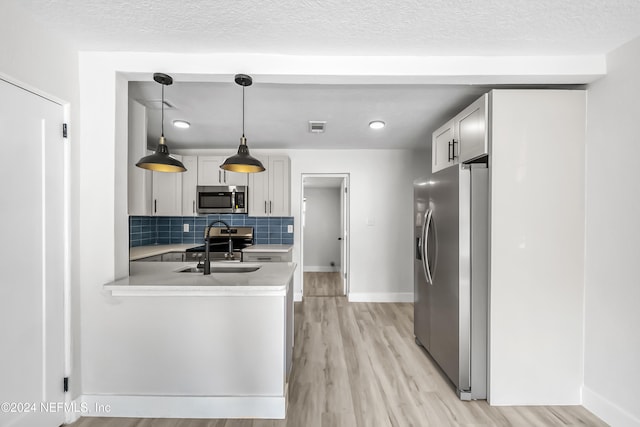 kitchen featuring sink, decorative backsplash, light wood-type flooring, decorative light fixtures, and stainless steel appliances