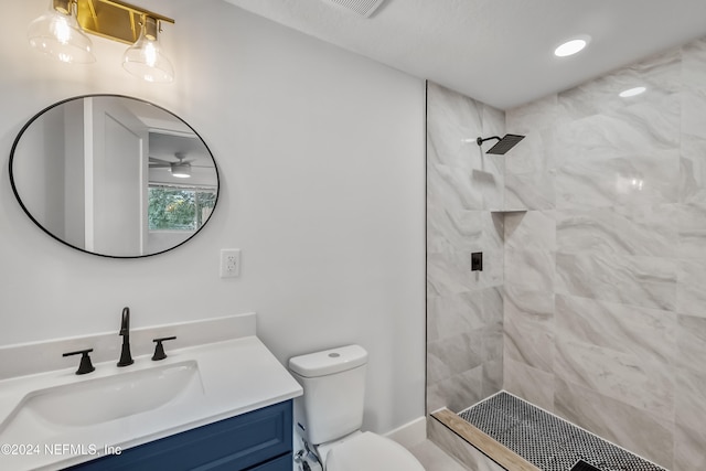 bathroom featuring a tile shower, vanity, and toilet