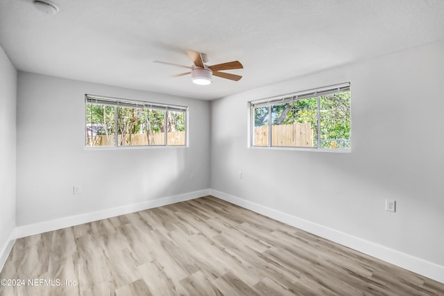 empty room featuring ceiling fan, a healthy amount of sunlight, and light hardwood / wood-style floors