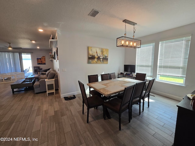 dining area featuring ceiling fan, wood-type flooring, and a textured ceiling