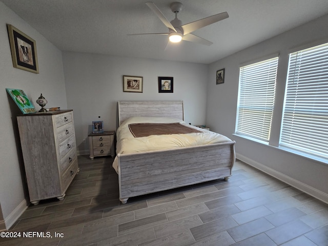 bedroom featuring ceiling fan, wood-type flooring, and a textured ceiling