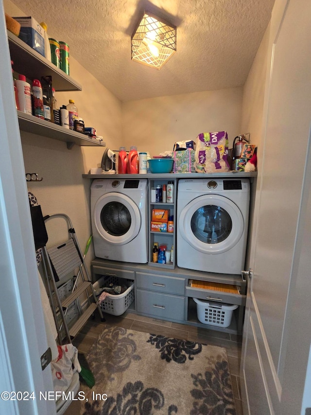 laundry area featuring washing machine and clothes dryer, tile patterned flooring, and a textured ceiling