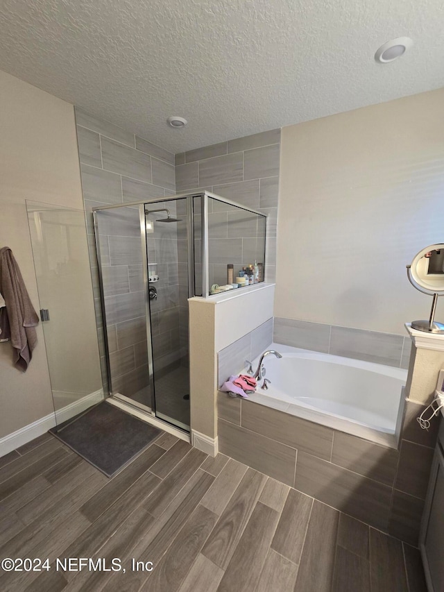 bathroom with shower with separate bathtub and a textured ceiling