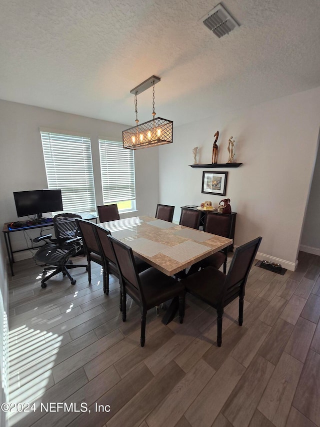 dining room with a textured ceiling and dark hardwood / wood-style floors