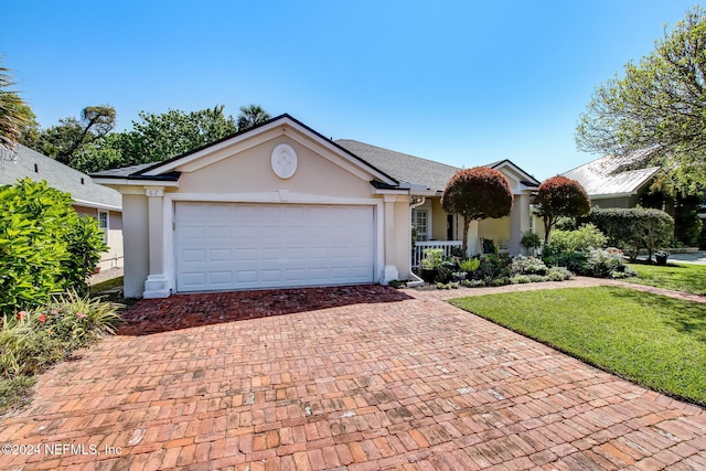 single story home featuring covered porch, a garage, and a front yard